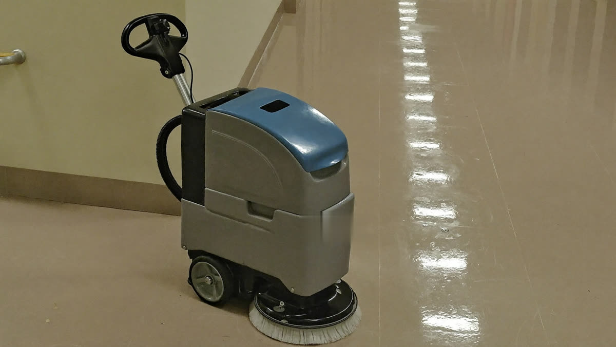Commercial floor scrubber in a polished office hallway with a freshly cleaned floor